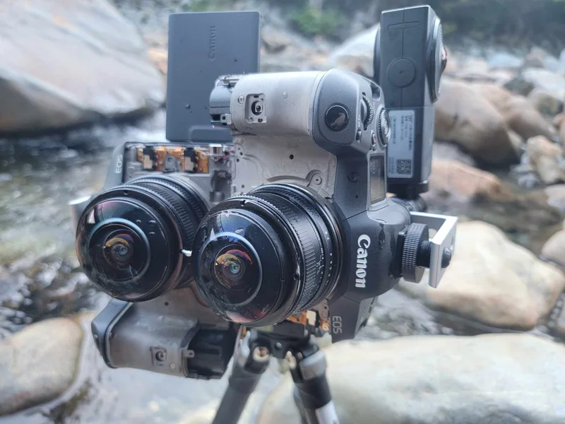 Modified dual Canon R5 stereoscopic camera rig outside by rocks/water.
