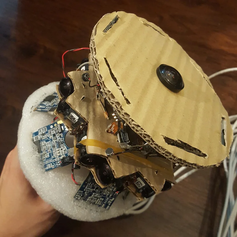 Hand-held multi-camera prototype with cardboard shell and exposed electronics.