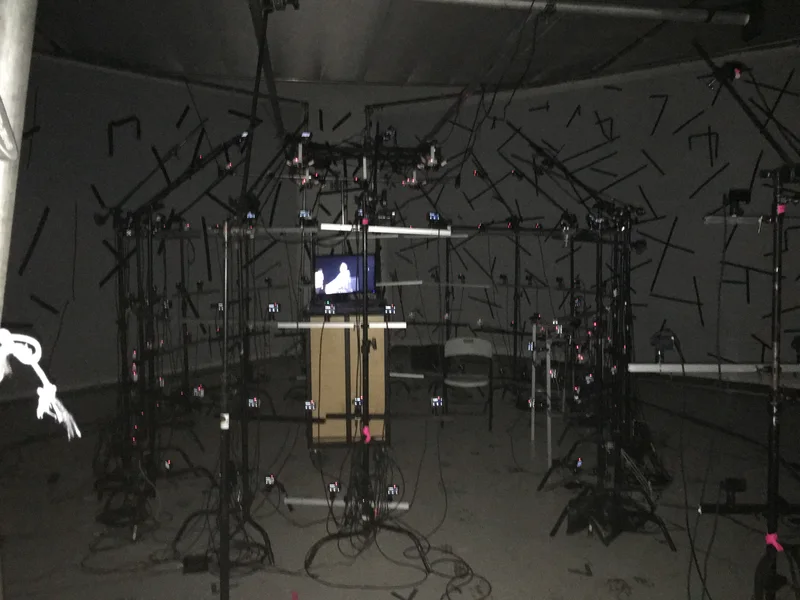 Low-light stage with witness monitor, lighting and camera supports.