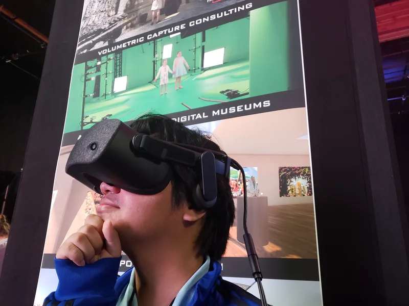 Participant wearing a VR headset in front of the partner booth display.
