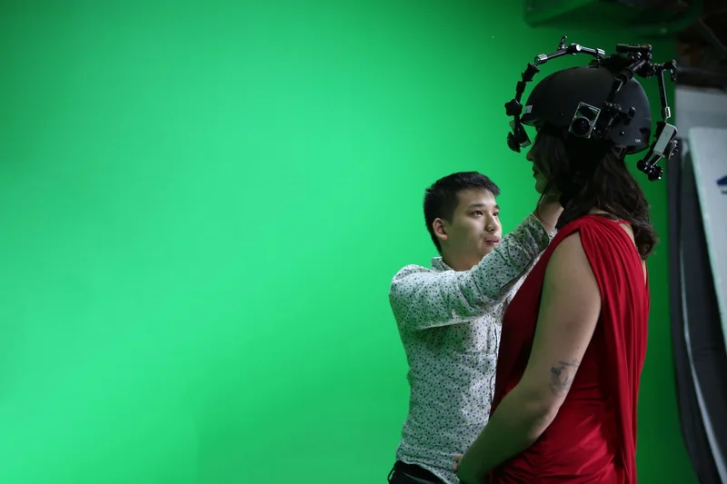 Capture equipment being adjusted around a performer against a green screen.