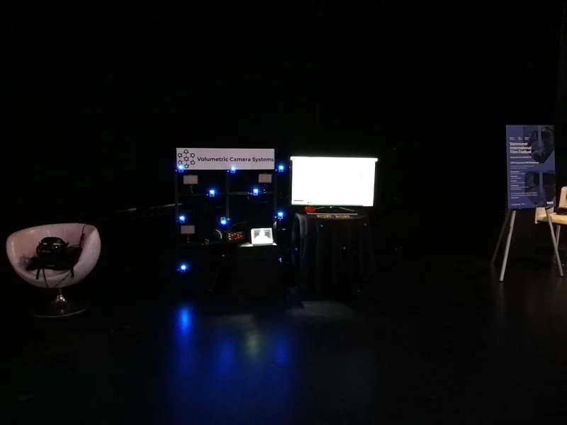 Alternate wide view of the dark VCS booth, camera array, monitor and VR chair.