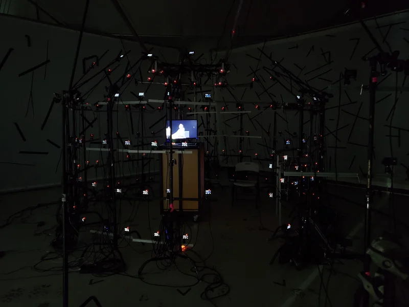 Alternate dark studio camera-array photograph with monitor and surrounding equipment.